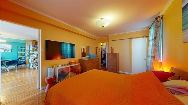 bedroom featuring wood-type flooring, a walk in closet, a closet, and crown molding