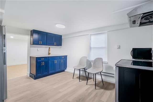 kitchen with blue cabinetry and light hardwood / wood-style floors