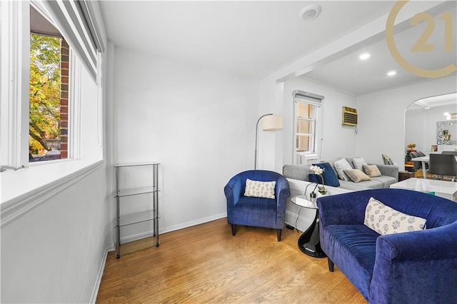 living room with a wall mounted air conditioner and light wood-type flooring