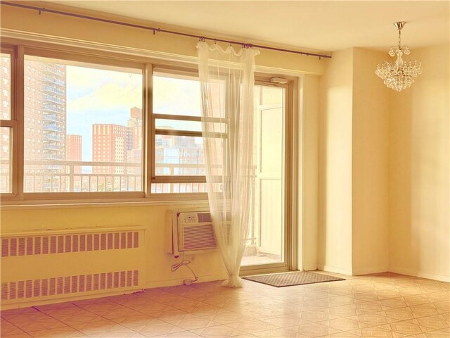 unfurnished room featuring radiator heating unit, an inviting chandelier, a wealth of natural light, and an AC wall unit