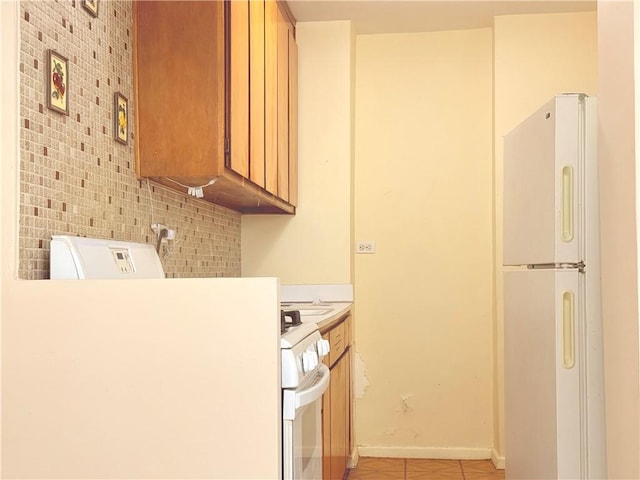 kitchen featuring light tile patterned flooring, white fridge, and stove