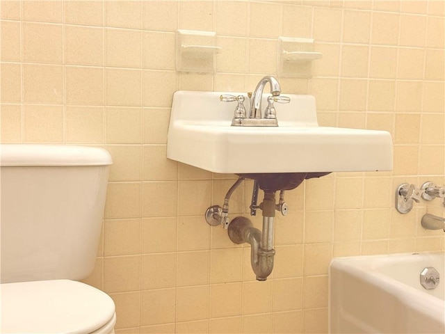 bathroom featuring sink, tile walls, a bathtub, and toilet