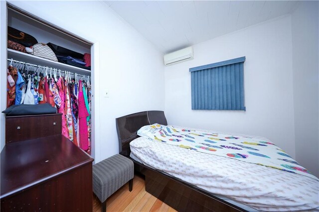 bedroom with hardwood / wood-style flooring and an AC wall unit