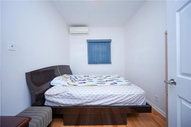 bedroom featuring wood-type flooring and a wall mounted AC