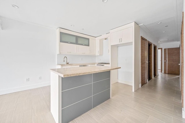 2335 Bath Ave Unit 1A, Brooklyn, NY 11214 - kitchen with a sink, a center island, white cabinets, glass insert cabinets, and baseboards