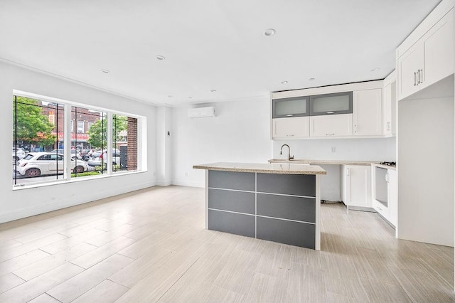 2335 Bath Ave Unit 1A, Brooklyn, NY 11214 - kitchen featuring a kitchen island, white cabinets, a wall unit AC, glass insert cabinets, and light wood finished floors