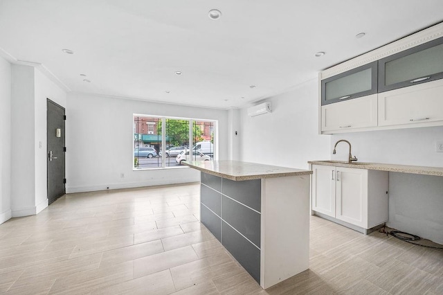 2335 Bath Ave Unit 1A, Brooklyn, NY 11214 - kitchen with a sink, white cabinets, a center island, a wall mounted AC, and light stone countertops