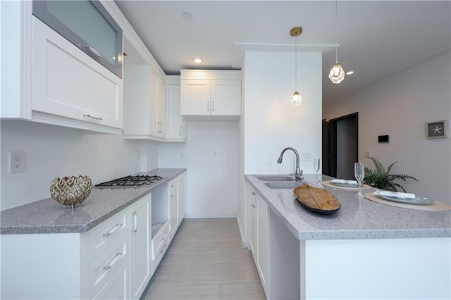 kitchen with a sink, white cabinets, stainless steel gas stovetop, and a peninsula