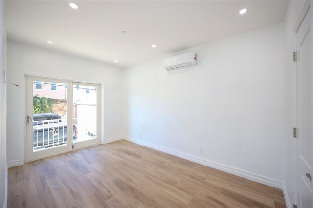 spare room featuring light hardwood / wood-style floors and a wall unit AC