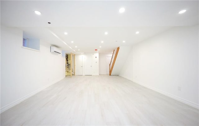 basement with a wall unit AC and light wood-type flooring