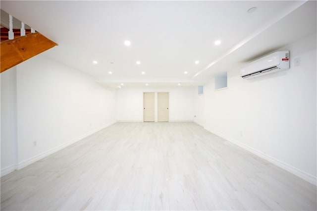 basement featuring an AC wall unit and light hardwood / wood-style floors