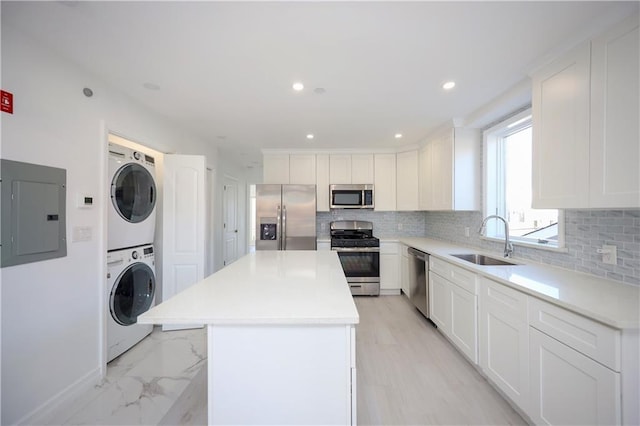 kitchen featuring sink, stainless steel appliances, stacked washer / dryer, electric panel, and a kitchen island