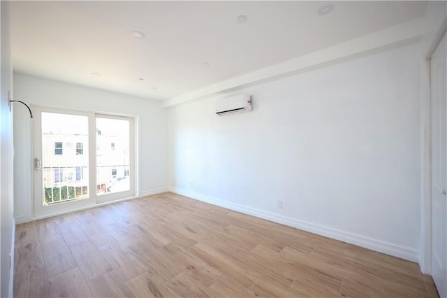 empty room with a wall mounted air conditioner and light wood-type flooring