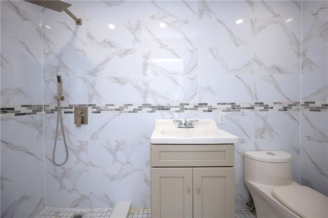 bathroom featuring a tile shower, vanity, toilet, and tile walls