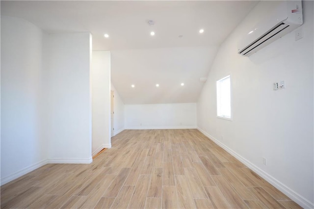 additional living space featuring light hardwood / wood-style flooring, an AC wall unit, and lofted ceiling