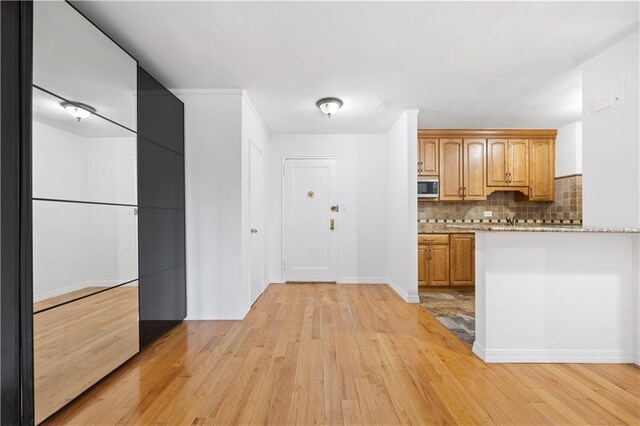 kitchen with light stone countertops, light wood-type flooring, and tasteful backsplash