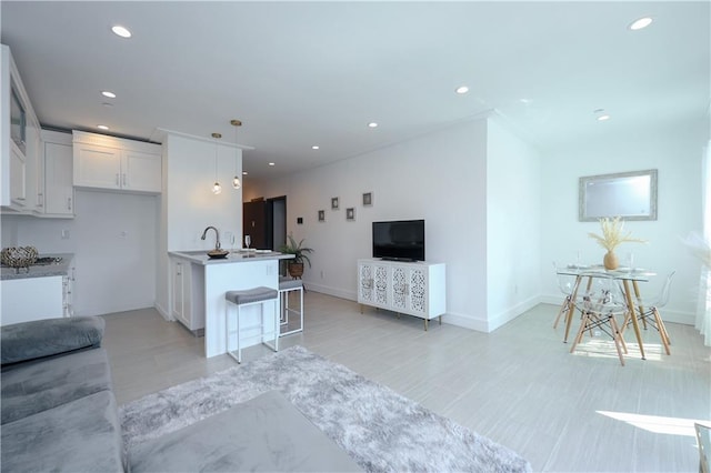 kitchen featuring white cabinets, recessed lighting, open floor plan, and a kitchen breakfast bar