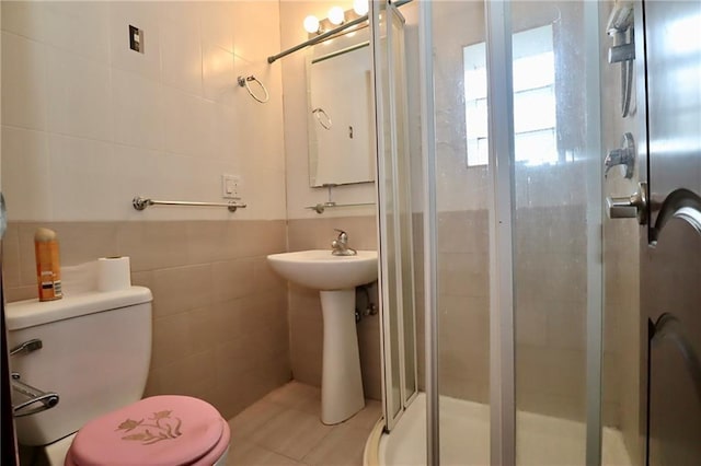 bathroom featuring a shower stall, tile walls, and toilet