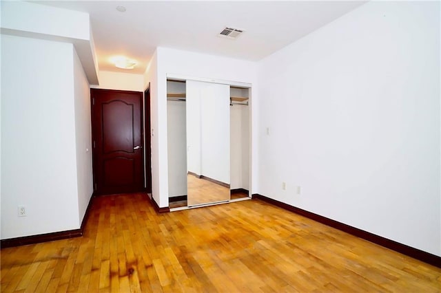 unfurnished bedroom with light wood-style floors, baseboards, visible vents, and a closet