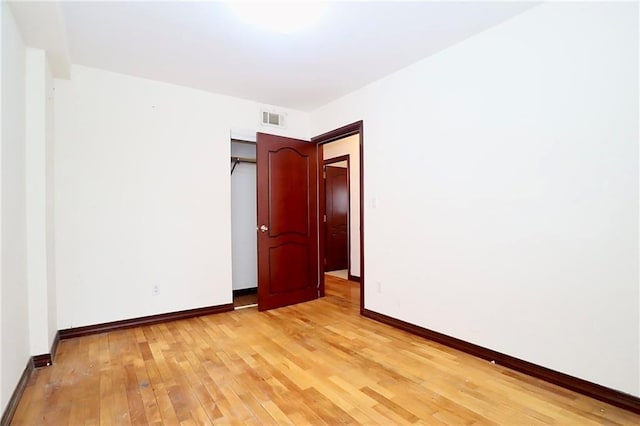 empty room featuring light wood-type flooring, visible vents, and baseboards