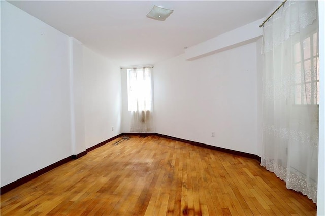 empty room featuring baseboards and light wood finished floors