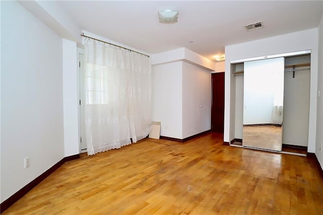 unfurnished bedroom featuring hardwood / wood-style flooring, baseboards, and visible vents