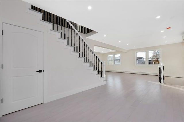 foyer entrance with stairs, a baseboard heating unit, light wood-style flooring, and recessed lighting