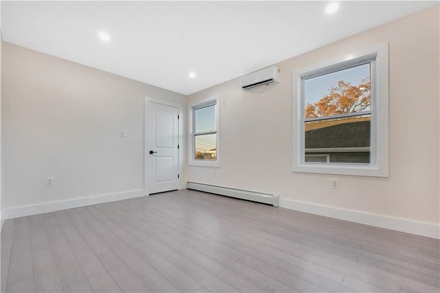 spare room featuring a baseboard heating unit, light wood-style floors, baseboards, and a wall mounted AC