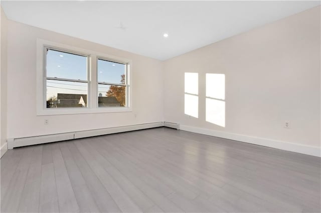 spare room featuring light hardwood / wood-style floors, a baseboard radiator, and lofted ceiling