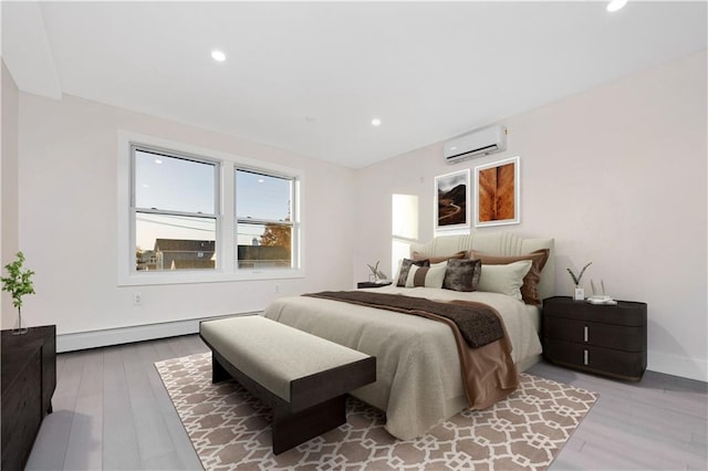 bedroom with recessed lighting, a baseboard heating unit, wood finished floors, a wall mounted air conditioner, and baseboards