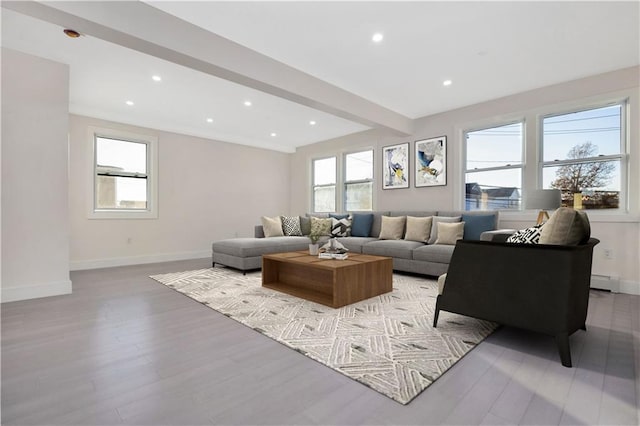 living room with a healthy amount of sunlight, light hardwood / wood-style floors, and beamed ceiling