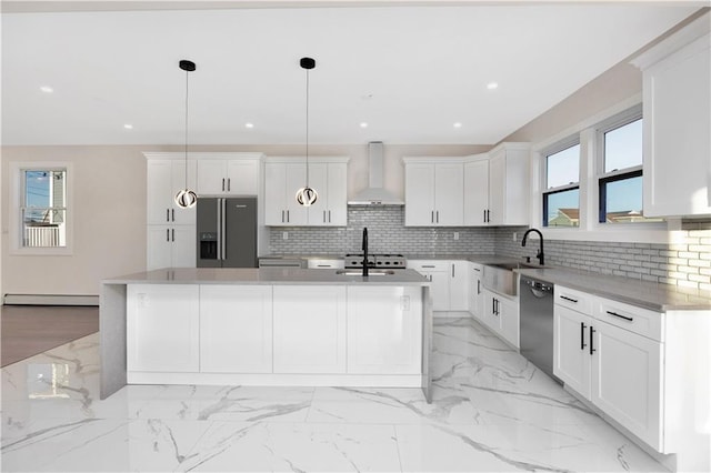 kitchen with appliances with stainless steel finishes, wall chimney range hood, pendant lighting, and a kitchen island