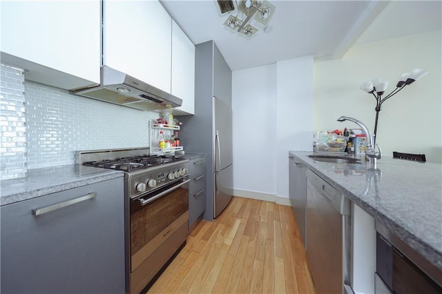 kitchen with white cabinets, appliances with stainless steel finishes, extractor fan, and light stone counters