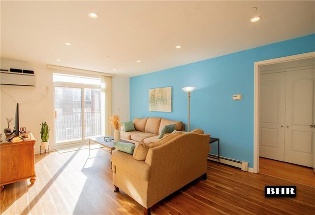 living room with wood-type flooring, a wall unit AC, and baseboard heating