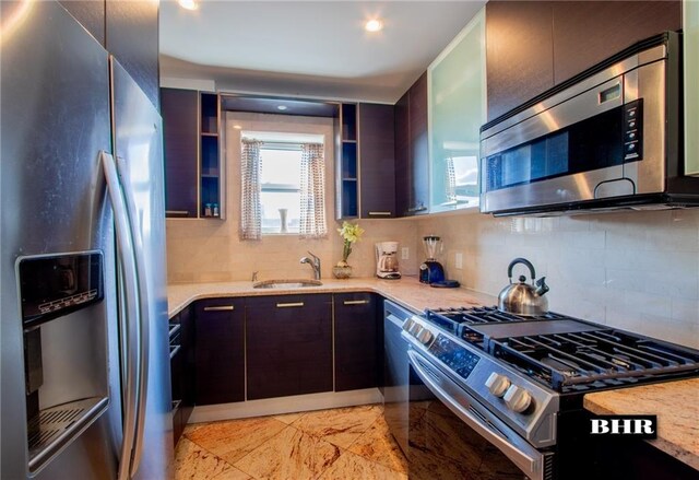 kitchen with stainless steel appliances, tasteful backsplash, dark brown cabinets, and sink