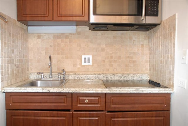 kitchen with tasteful backsplash, black electric cooktop, and sink