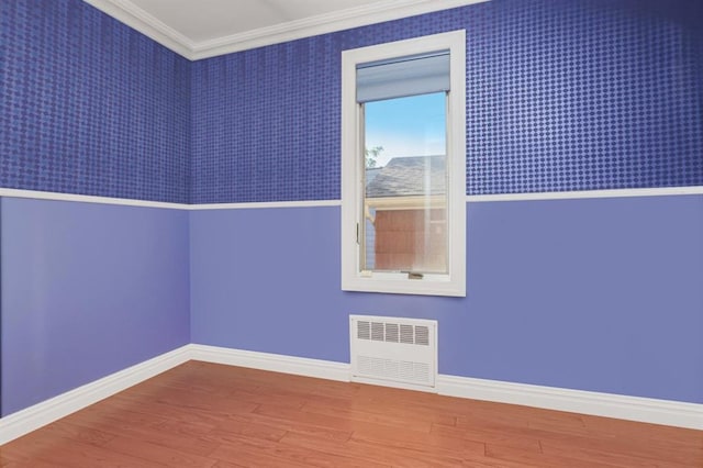 spare room with hardwood / wood-style flooring, ornamental molding, and radiator