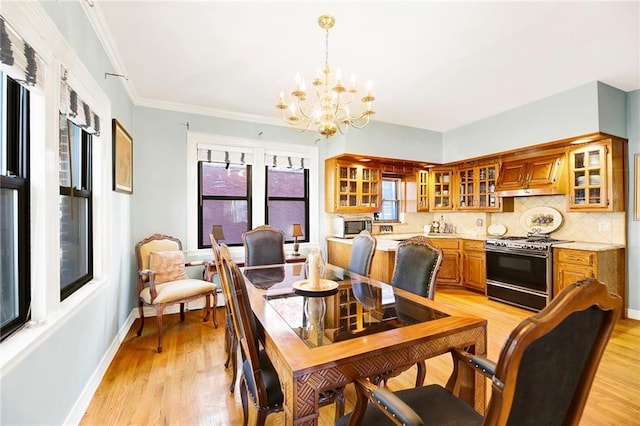 dining space featuring light hardwood / wood-style flooring, crown molding, and an inviting chandelier