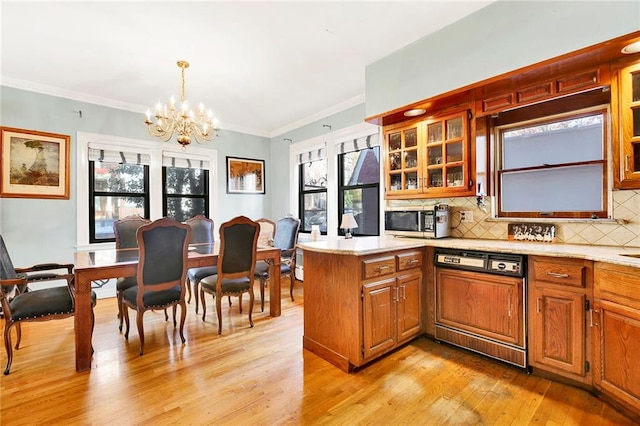 kitchen featuring paneled dishwasher, backsplash, a notable chandelier, light wood-type flooring, and pendant lighting