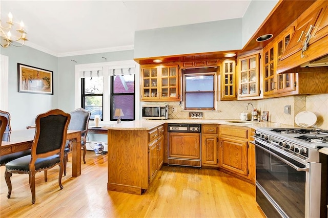 kitchen featuring kitchen peninsula, stainless steel appliances, tasteful backsplash, a chandelier, and sink