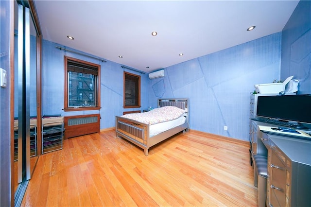 bedroom with recessed lighting, radiator heating unit, a wall mounted AC, and wood finished floors