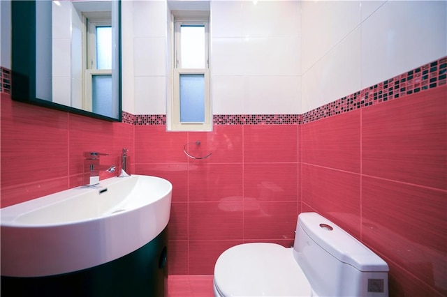 half bath featuring vanity, tile walls, and toilet