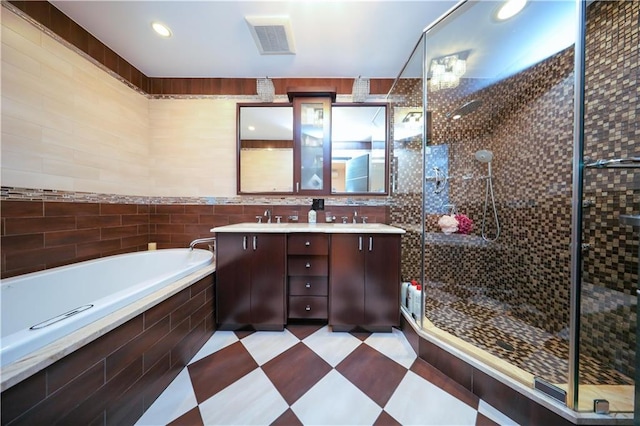 full bathroom featuring visible vents, double vanity, a sink, a shower stall, and a garden tub