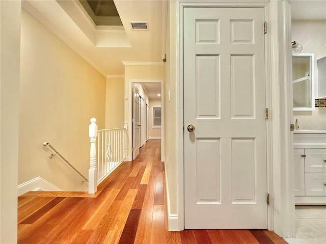 corridor with ornamental molding and light hardwood / wood-style flooring