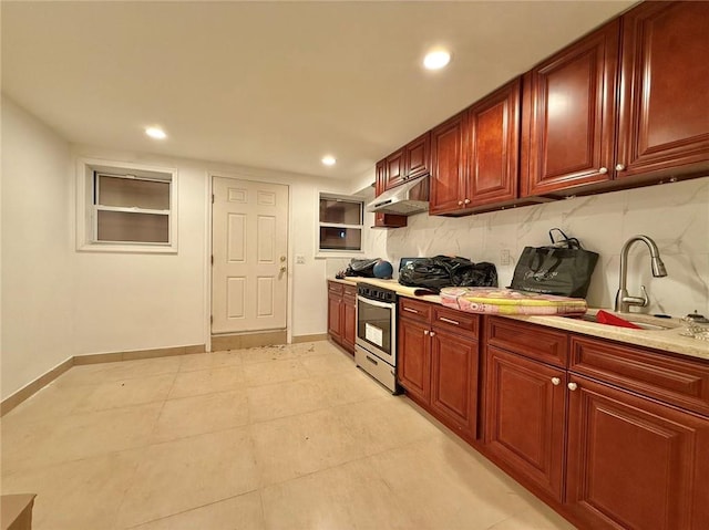 kitchen featuring stainless steel range, light stone countertops, sink, and decorative backsplash