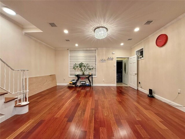 spare room with hardwood / wood-style flooring, crown molding, and an inviting chandelier