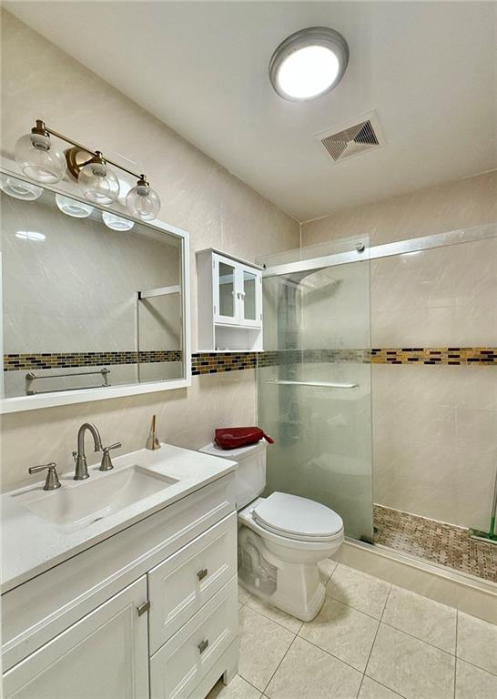 bathroom featuring an enclosed shower, vanity, toilet, and tile patterned flooring