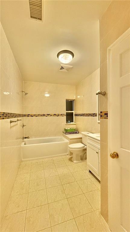 bathroom featuring toilet, tile walls, tile patterned floors, and vanity