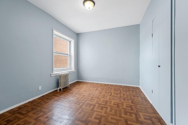 spare room with dark parquet flooring and radiator