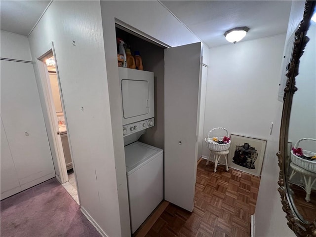 laundry area with dark parquet floors and stacked washing maching and dryer